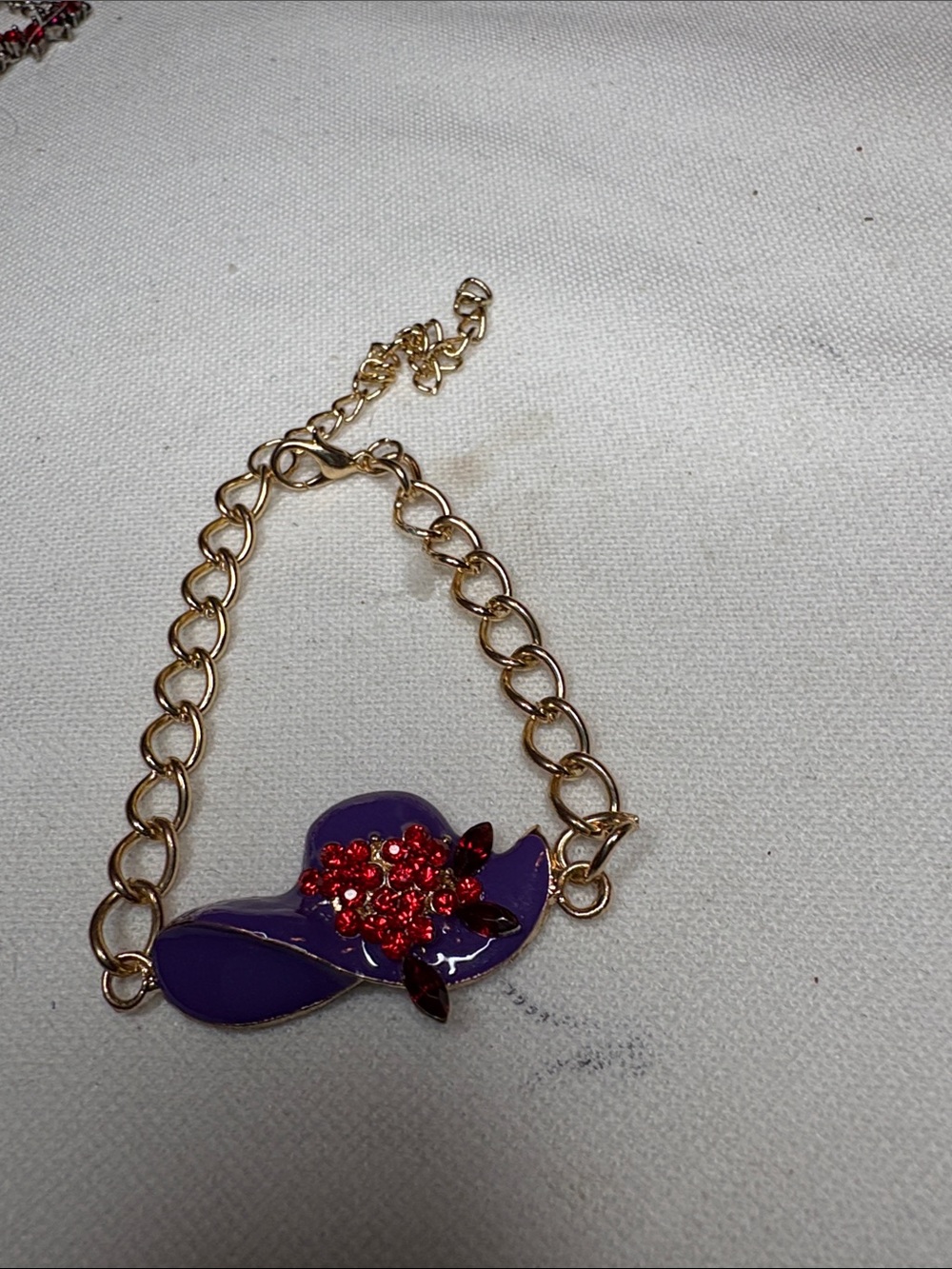 Gold-Tone Bracelet with Purple Hat Charm and Red Crystal Accent